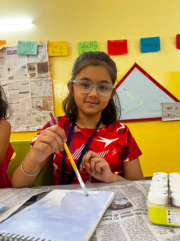 A girl painting at the summer camp art table