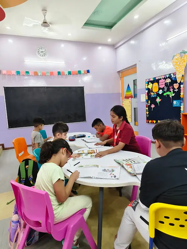 Children do their homework at a round table with a staff member in the day care room