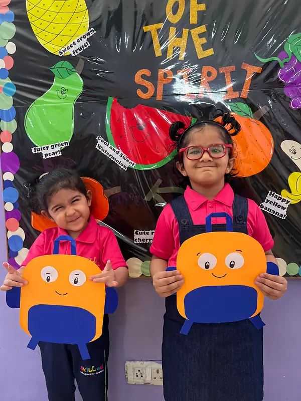 Two girls grinning with the paper backpacks they made on the first day back